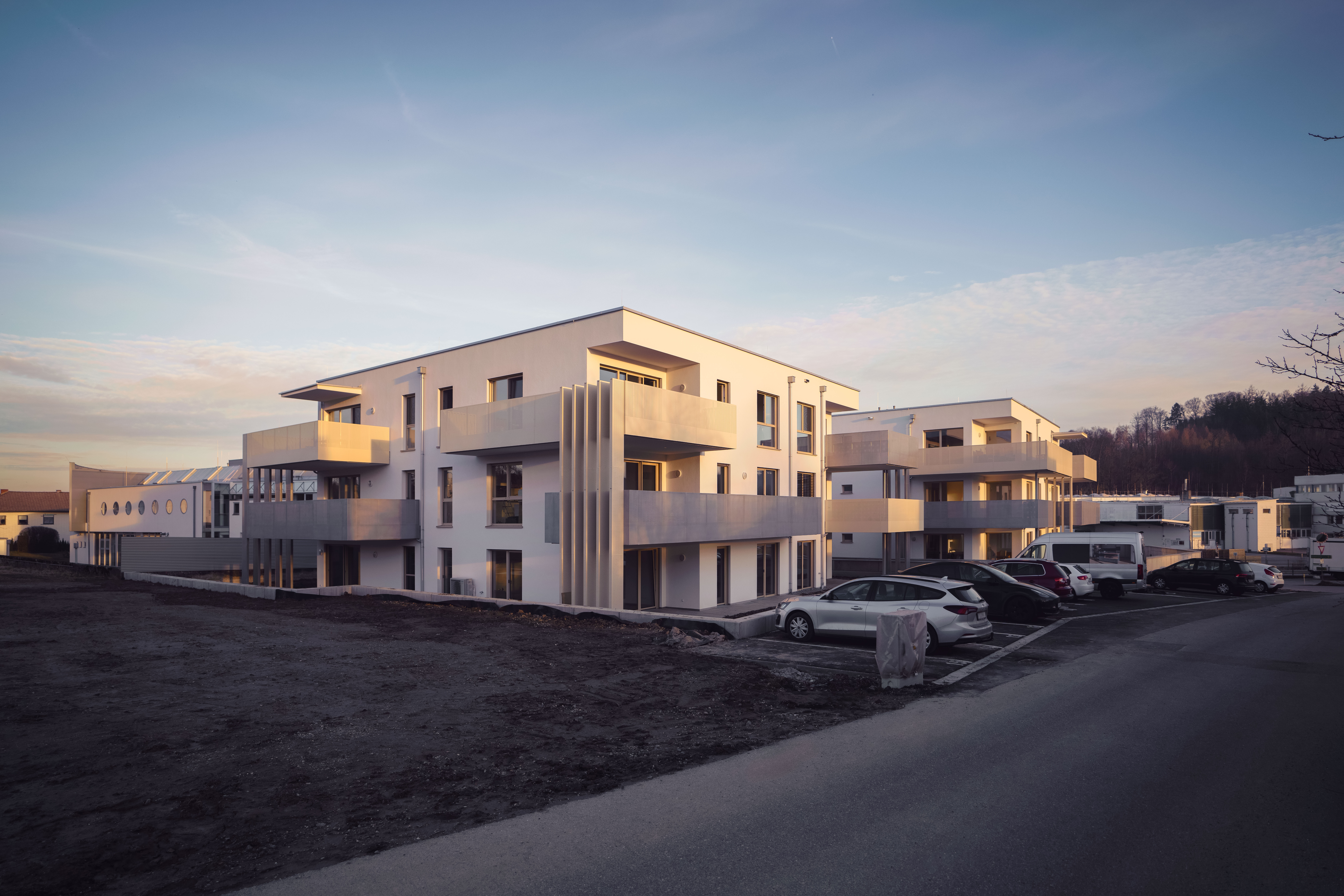 Mehrfamilienhaus Sternvillen Gaspoltshofen mit Fenstern und Balkonen von Revolux, Außenansicht in der Abendsonne