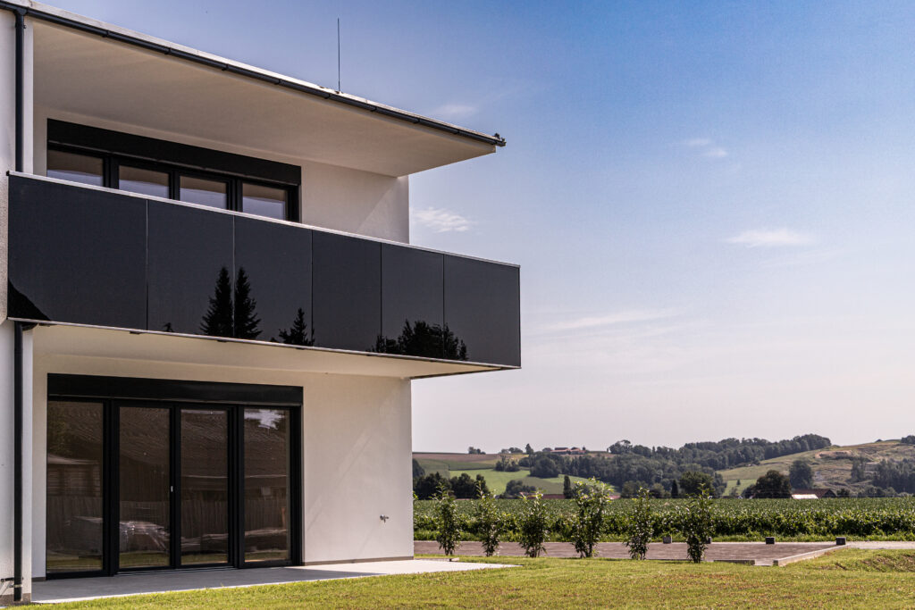 Modernes Einfamilienhaus mit hochwertigen Aluminiumfenstern, Fenstertüren und Balkon in zeitloser Architektur.