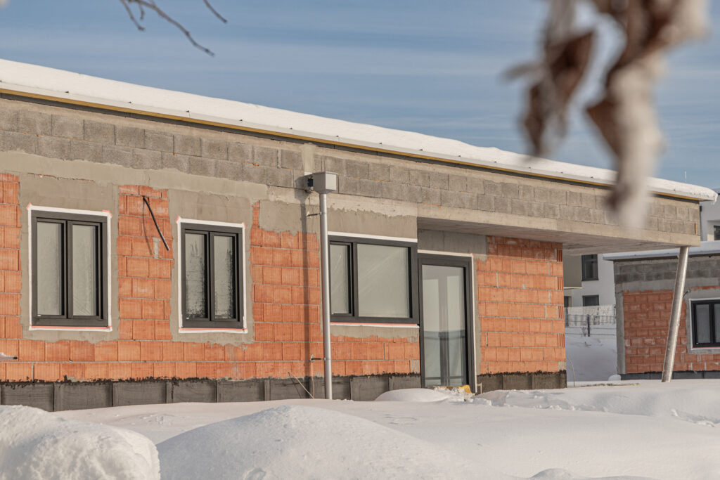 Moderner Bungalow im Bau mit energieeffizienten Revolux-Fenstern und großer Terrassentür.